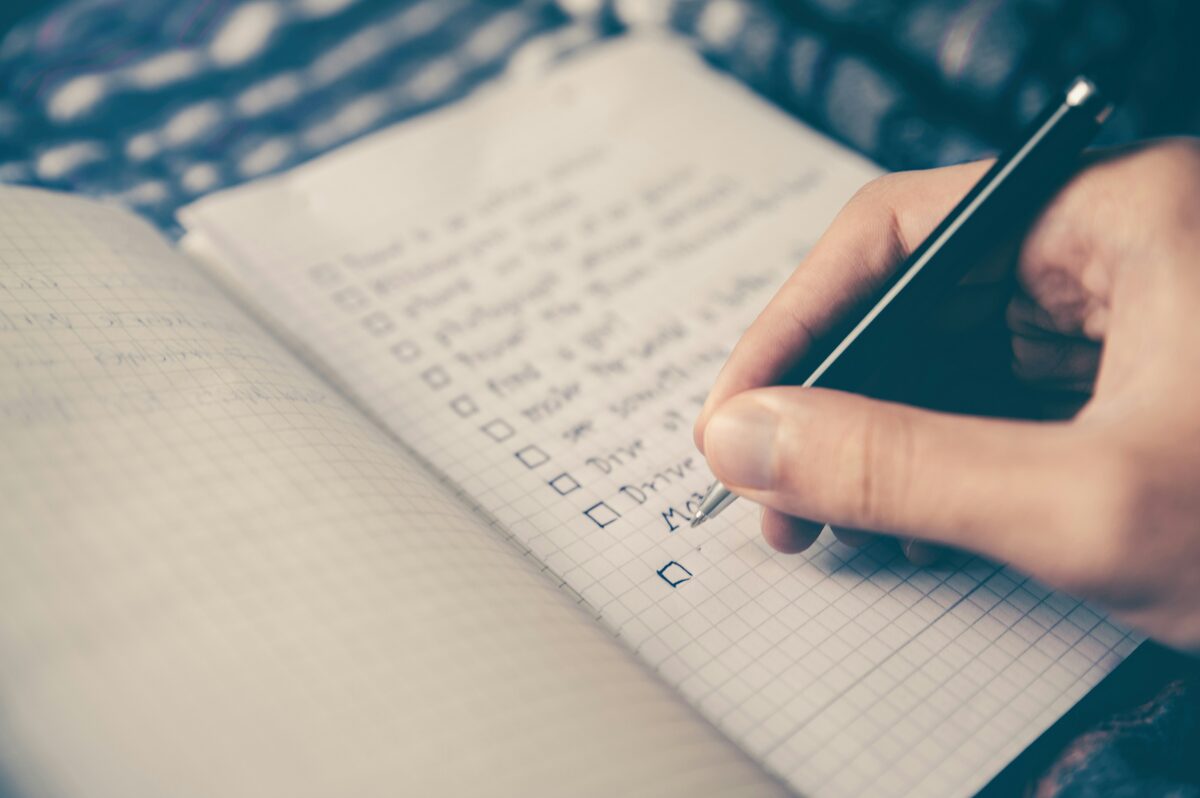 A hand checking off items on a handwritten checklist, representing reviewing answers for correctness